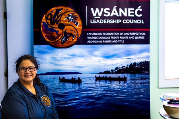 W̱SÁNEĆ Leadership Council's Marine Use Planner Shauna Johnson stand on front of a WLC sign.